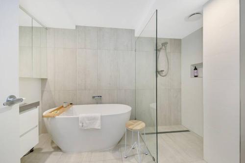 a white bathroom with a tub and a glass shower at Hampton's Style Beach Retreat in Noosa's Heart in Noosa Heads