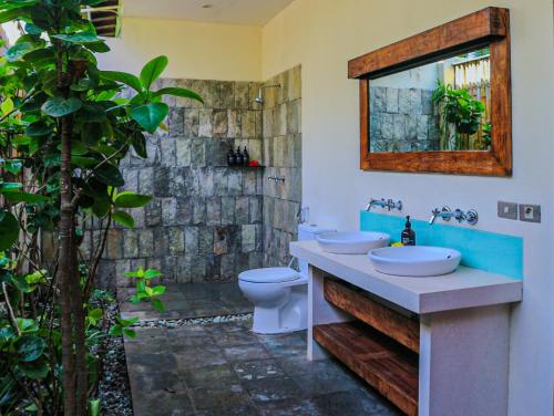 a bathroom with a sink and a toilet and a mirror at Dolce Magia in Gili Trawangan