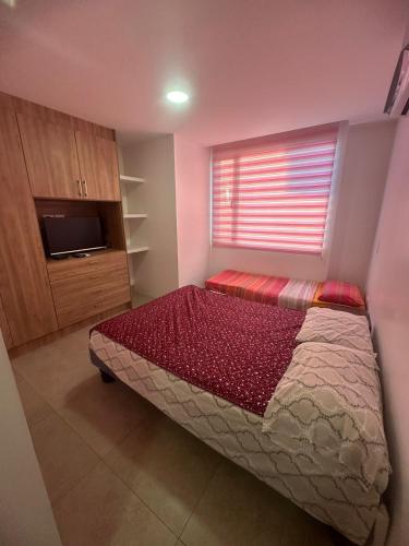 a bedroom with a bed with a window and a television at Chipipe Salinas in Salinas