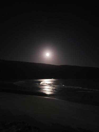a full moon rising over the beach at night at imsouane bleu bay house in Imsouane