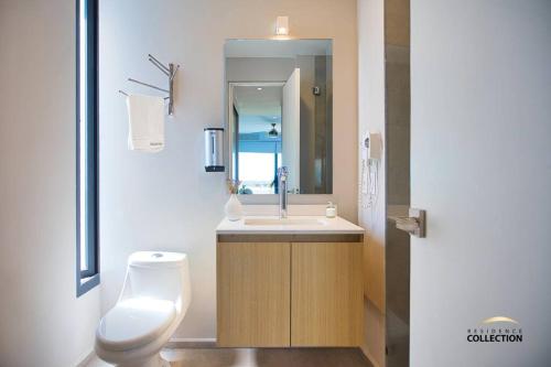 a bathroom with a toilet and a sink with a mirror at Nuevo Estudio en Aria Ocean 609 in Nuevo Vallarta
