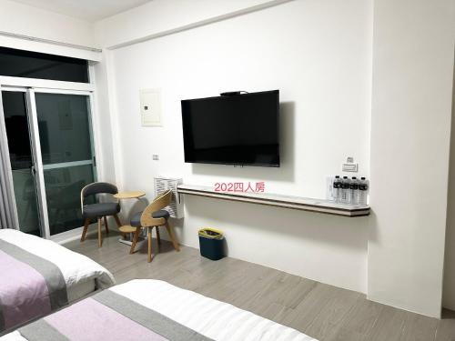 a room with a tv on a wall with a bed at Xiaomi Courtyard B&B in Chishang
