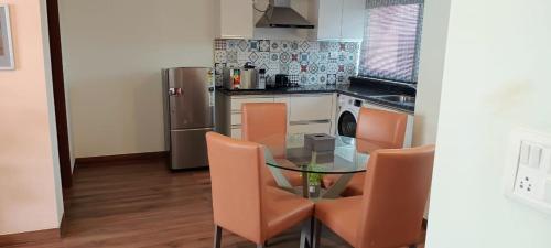 a kitchen with a glass table and orange chairs at Carnival De Goa in Nerul