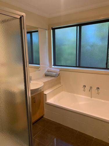 a bathroom with a tub and a sink and a window at Cowes Luxury Getaway in Cowes