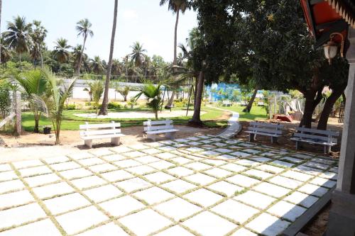 a park with white benches and palm trees at Athulya Resort -Leisure and Luxury cottages from EMBEHolidays in Kottaikadu