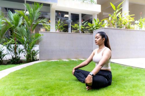 a woman sitting on the grass in front of a building at Carnival De Goa in Nerul