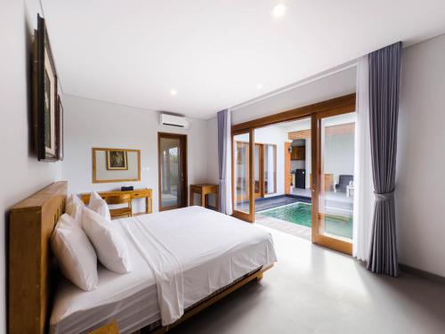 1 dormitorio con 1 cama y puerta corredera de cristal en Yuta Villa Ubud, en Ubud
