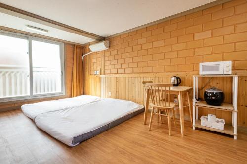 a bedroom with a bed and a table and a microwave at Red Clay Pension in Jeju