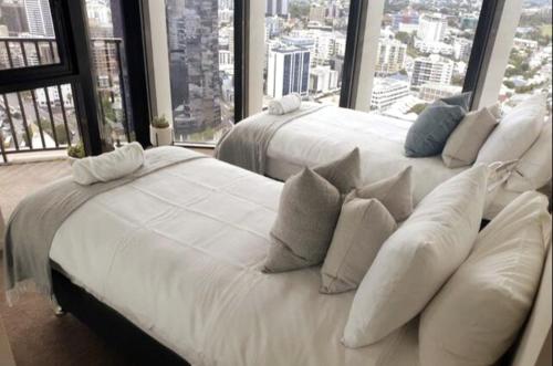 two white beds in a room with large windows at Executively Inspired - The Hutt in Brisbane