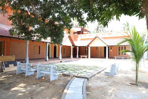 a courtyard of a building with benches in front of it at Athulya Resort -Leisure and Luxury cottages from EMBEHolidays in Kottaikadu