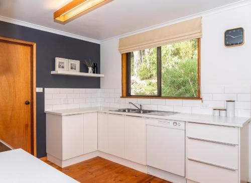 a white kitchen with a sink and a window at The Escarpment in Halls Gap