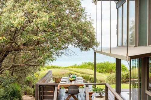 a table on a deck with a view of the ocean at One Hundred Banksias in Culburra Beach