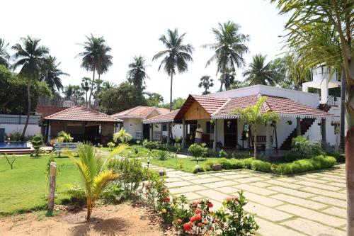 a house with a garden and palm trees in the background at Athulya Resort -Leisure and Luxury cottages from EMBEHolidays in Kottaikadu