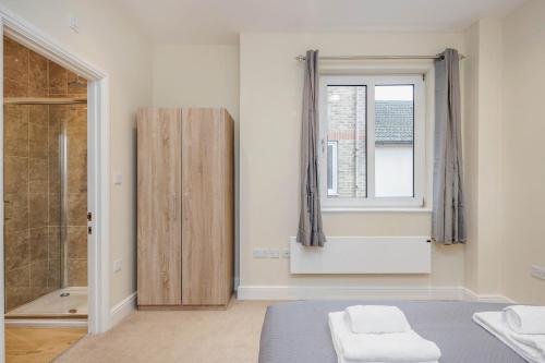 a bedroom with a bed and a window and a shower at Luxury Apartments 2 Bedrooms Central Maidenhead in Maidenhead