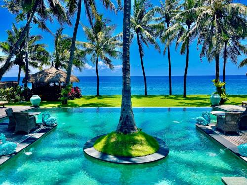 a pool with a palm tree in the middle at Louka Beach Bali in Tianyar