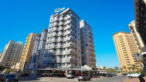 un grand bâtiment avec des voitures garées dans une ville dans l'établissement Saray Hotel Apartments, à Koweït
