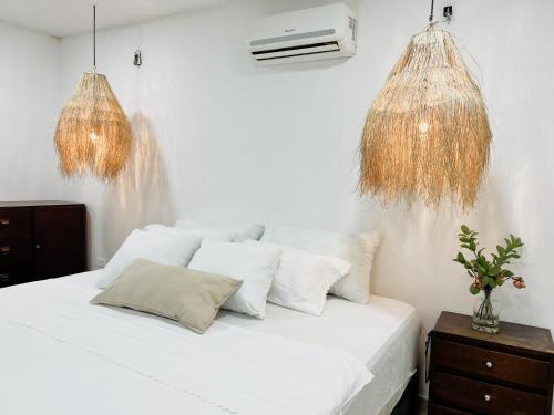 a bedroom with a bed with white sheets and gold chandeliers at Casa Maria campestre con piscina in Santa Marta