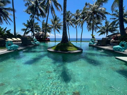 a pool at a resort with palm trees at Louka Beach Bali in Tianyar