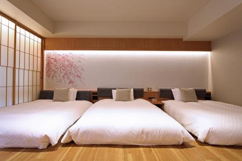 two beds in a room with white sheets at KAYA Kyoto Nijo Castle, BW Signature Collection by Best Western in Kyoto