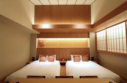 two beds in a room with chairs and windows at KAYA Kyoto Nijo Castle, BW Signature Collection by Best Western in Kyoto