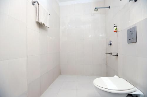 a white bathroom with a toilet and a shower at Hotel Mars Meg at Delhi Airport in New Delhi