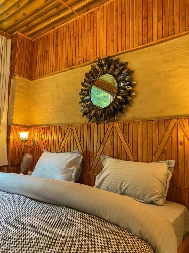 a bedroom with a bed with a mirror on the wall at Whoopers Boutique Resort Jibhi in Jibhi