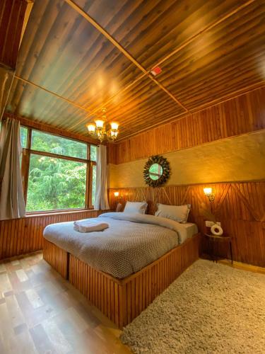 a bedroom with a large bed with a wooden ceiling at Whoopers Boutique Resort Jibhi in Jibhi