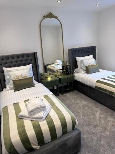 a bedroom with two beds and a mirror at Clarendon House - Hot Tub in Lincolnshire