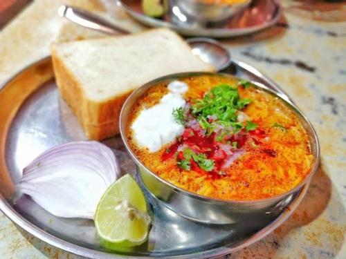 a bowl of soup on a plate with a slice of bread at Home Away From Home in Kolhapur