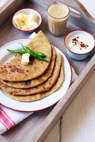 a plate of pancakes on a tray with a drink at Home Away From Home in Kolhapur