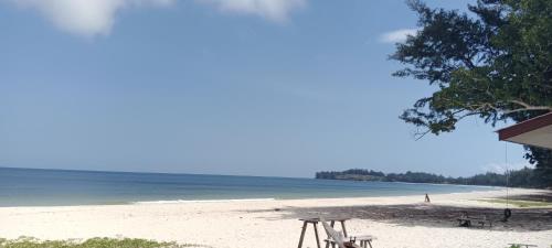 una playa con sillas y el océano en el fondo en Tumombuvoi homestay, en Tiga Papan