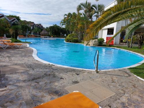 una gran piscina azul junto a una casa en Villa Privada en palma Real, en El Corazón