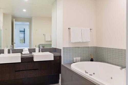 een badkamer met 2 wastafels en een bad bij Devine Rooftop Penthouse at Temple Resort in Port Douglas