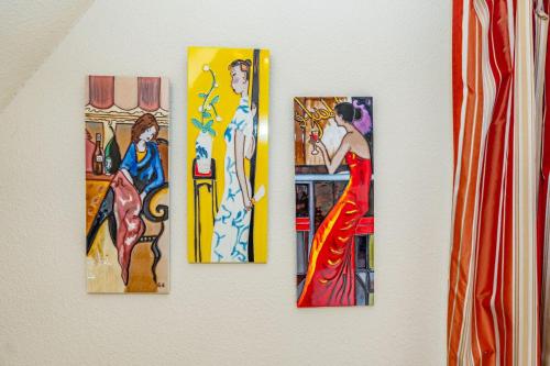 four paintings of women on a wall at WILDENTE-App-7 in Wenningstedt