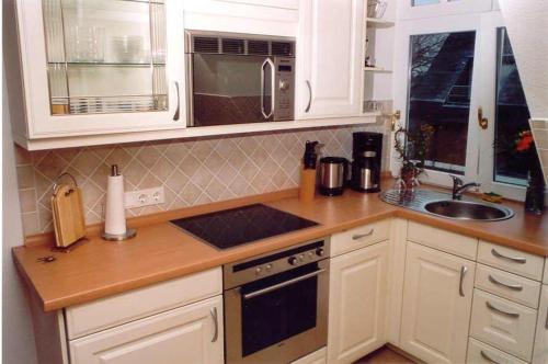 a kitchen with white cabinets and a sink at WILDENTE-App-7 in Wenningstedt