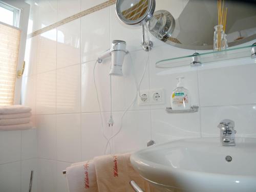 a white bathroom with a sink and a mirror at WILDENTE-App-7 in Wenningstedt