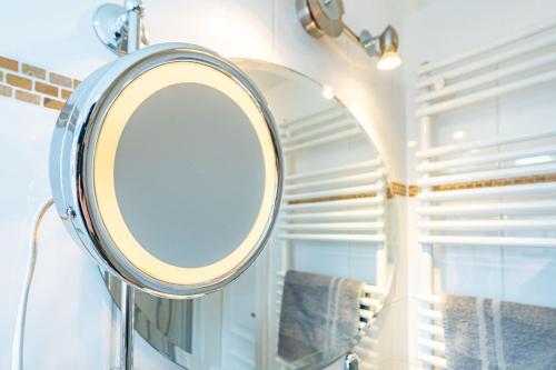 a round mirror in a bathroom with towels at WILDENTE-App-7 in Wenningstedt