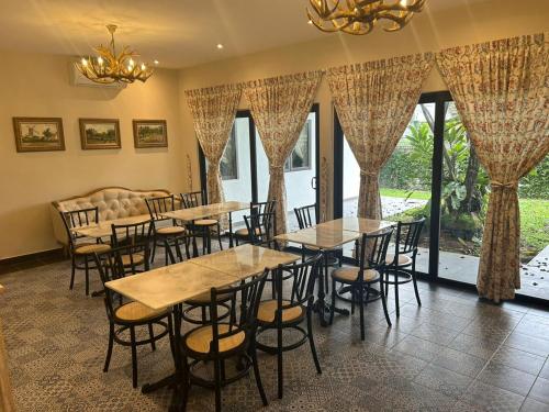 a group of tables and chairs in a room with windows at The Farmhouse in Ipoh