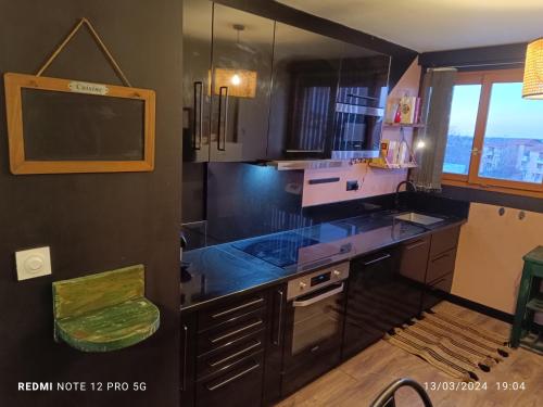 une cuisine avec un comptoir noir et une fenêtre dans l'établissement Magnifique appartement quartier la Roseraie, à Toulouse
