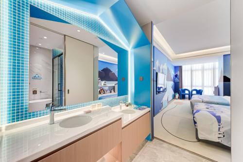 a blue bathroom with two sinks and a bed at Elephant Hotel in Zhuhai