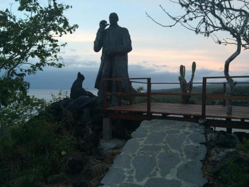a statue of a man standing next to a bench at Hotel Los Algarrobos in Puerto Baquerizo Moreno