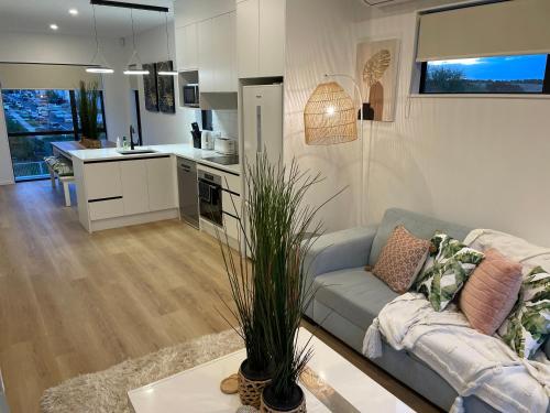 a living room with a couch and a kitchen at Flat Bush Holiday Accomodation in Auckland