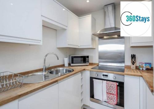 a white kitchen with a sink and a microwave at Luxury 1 Bedroom Apartment 06 with Parking in Maidenhead by 360stays in Maidenhead