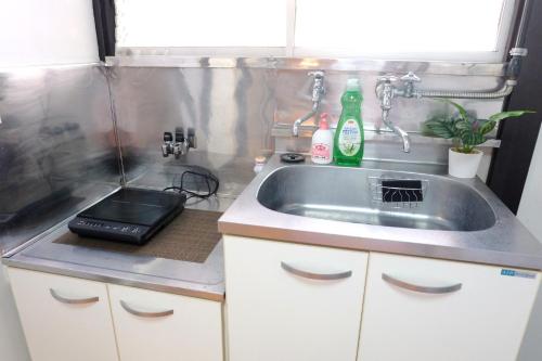 uma pequena cozinha com um lavatório e um fogão em green park heights - Vacation STAY 15687 em Musashino