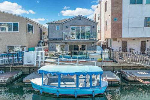 a blue boat docked at a dock with a house at Voted Airbnb Most Loved Home 2024 Duffy Boat in Huntington Beach