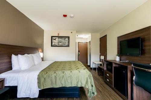 a hotel room with a bed and a flat screen tv at Quality Inn in Carrollton