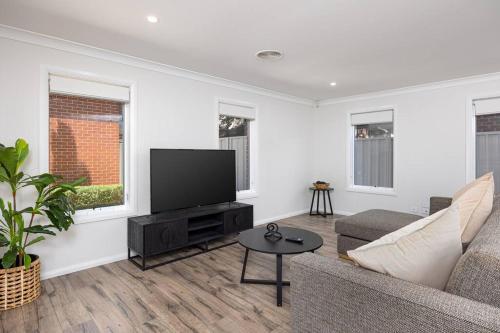 a living room with a couch and a flat screen tv at Stylish Urban Getaway in the Heart of the City in Wagga Wagga