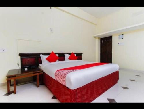 a bedroom with a bed with red pillows and a table at SK Residency in Vedal