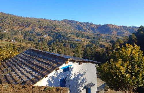 an old building with a mountain in the background at Idyllic Haven Heritage, Jageshwar in Jageshwar