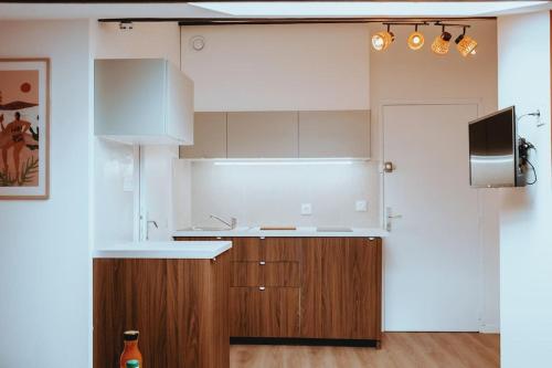a kitchen with white cabinets and a sink and a tv at Le Nid Douillet de l'Hypercentre in Toulouse
